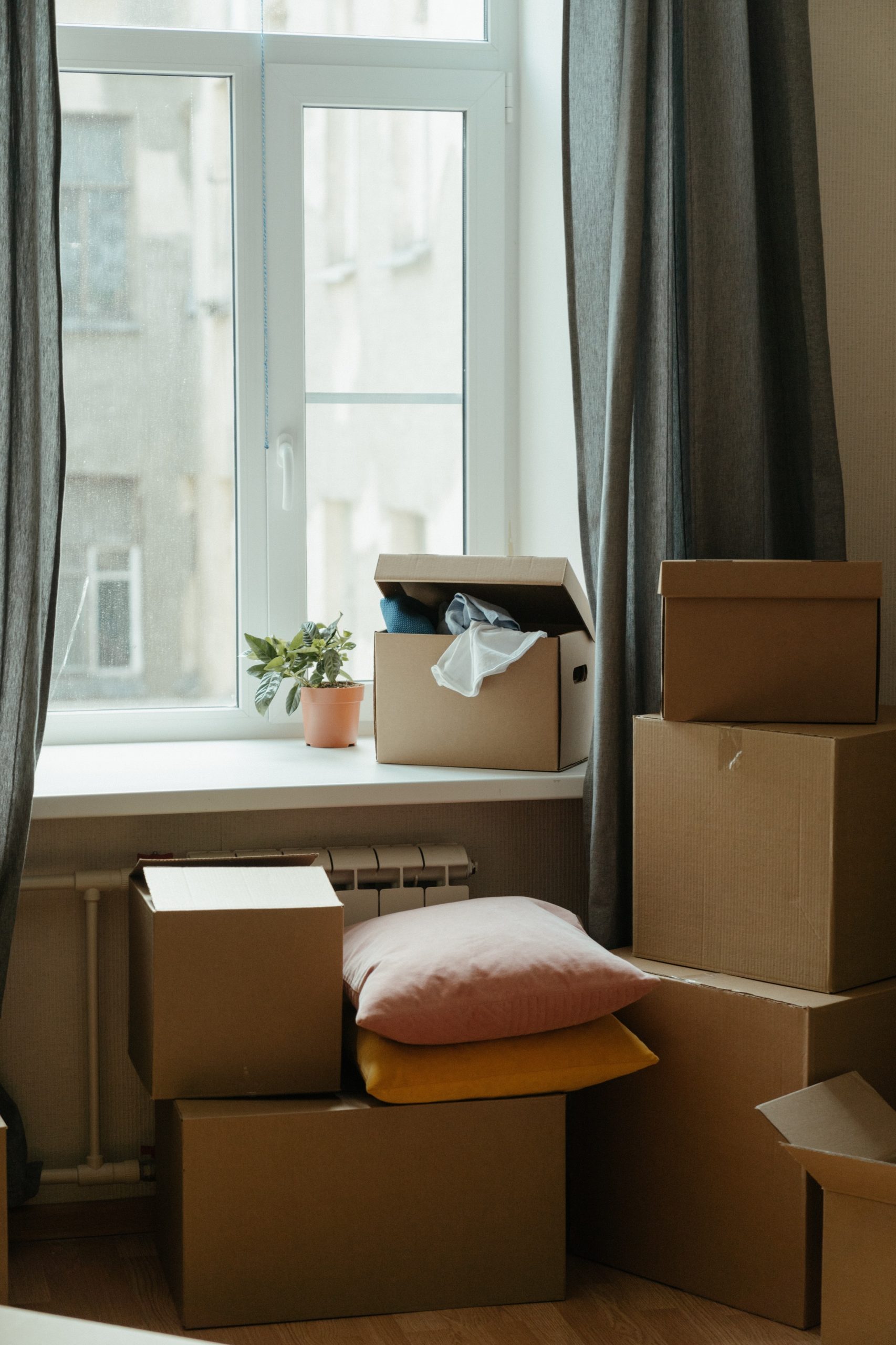 Moving boxes and pillows piled up near an open window